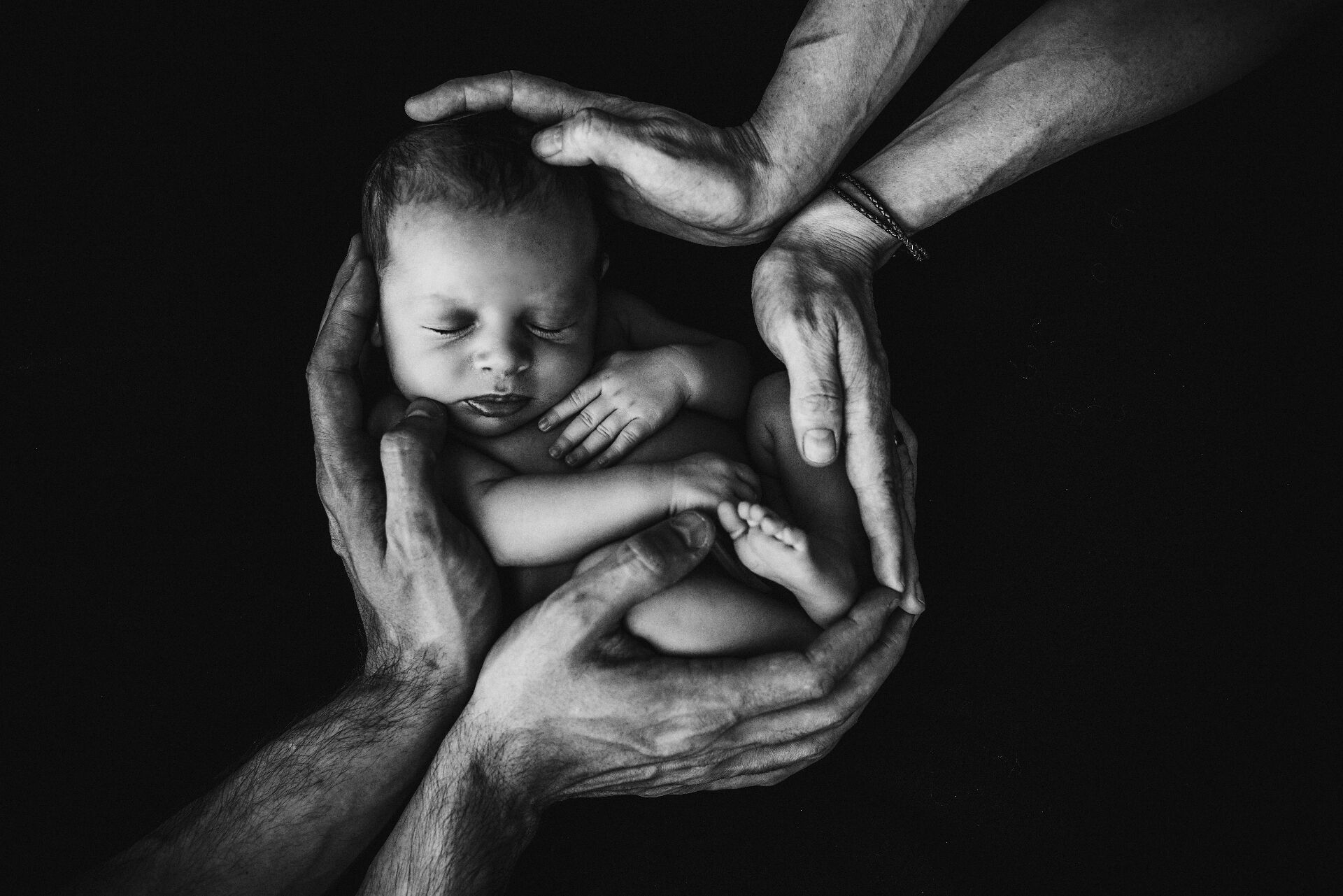 A newborn baby cradled in family hands